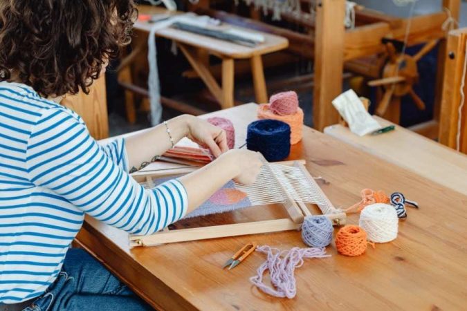 Artisan pratiquant l'artisanat français sur un métier à tisser avec des fils colorés