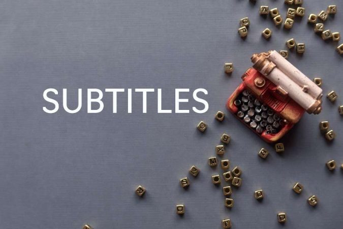 Le mot "SUBTITLES" écrit en lettres blanches sur un fond gris à côté d'une miniature de machine à écrire et de dés alphabétiques dorés.