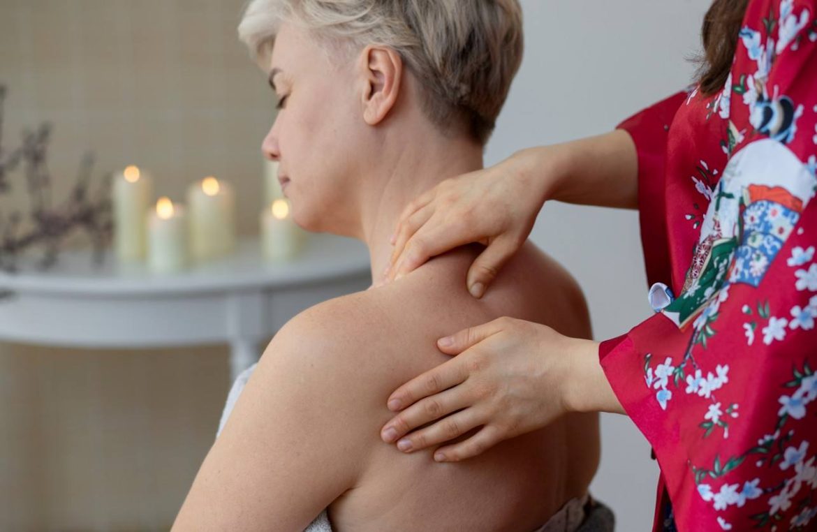 Personne recevant un massage du trapèze et des épaules dans une ambiance calme avec des bougies.