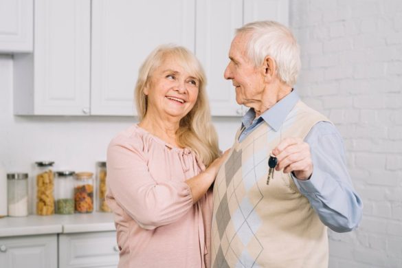 Couple senior souriant tenant les clés de leur logement adapté, illustrant l'impact vieillissement population immobilier.