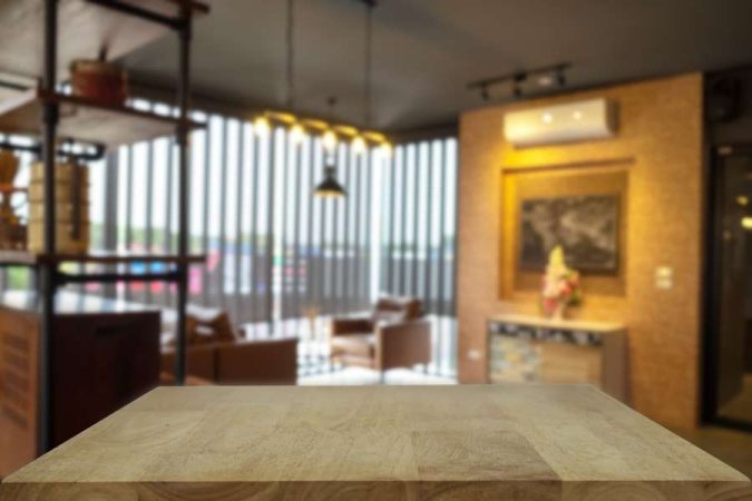Une table basse en bois massif placée dans un salon chaleureux à l'arrière-plan flouté.
